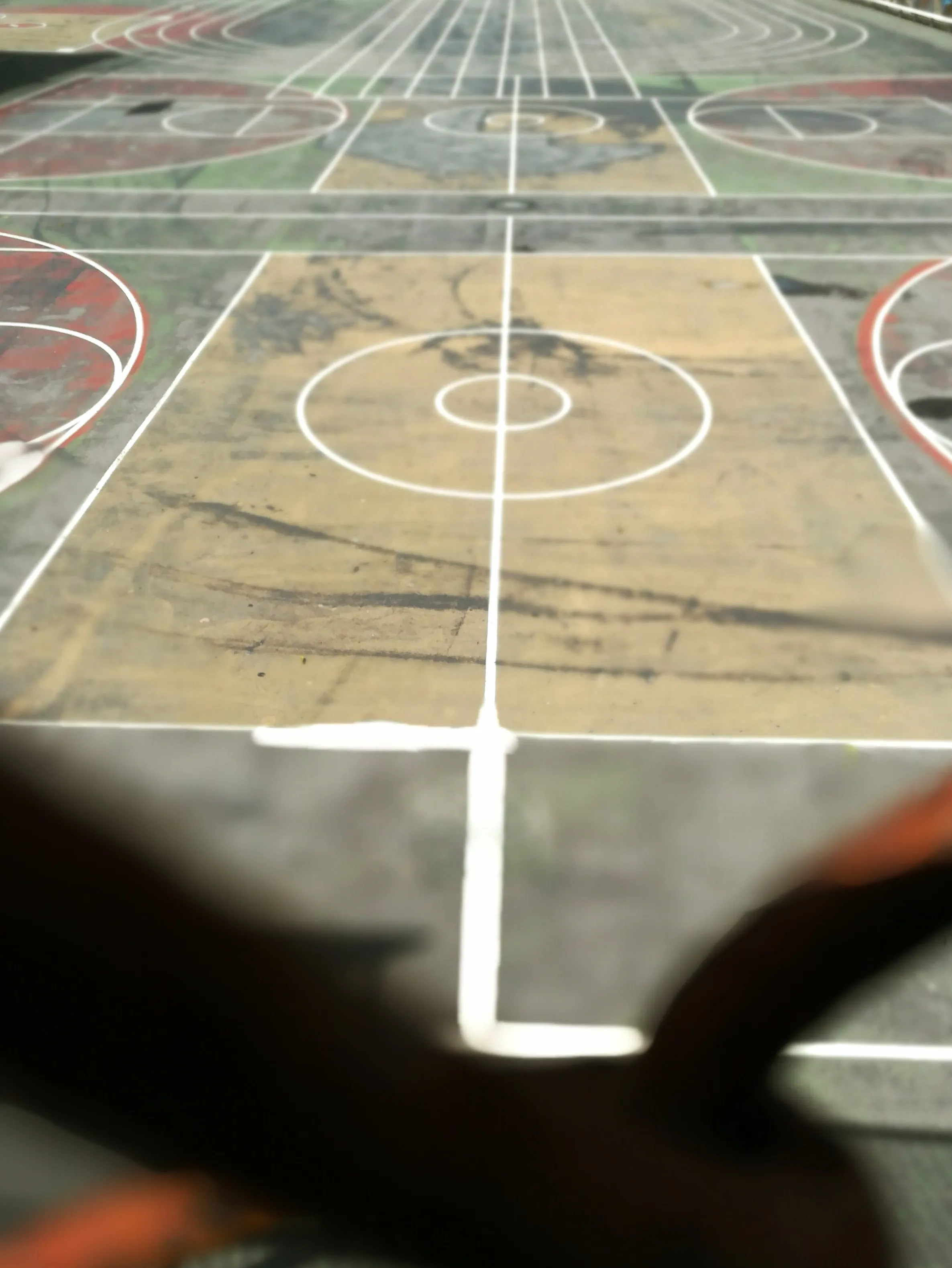 Faded outdoor basketball court seen from ground level