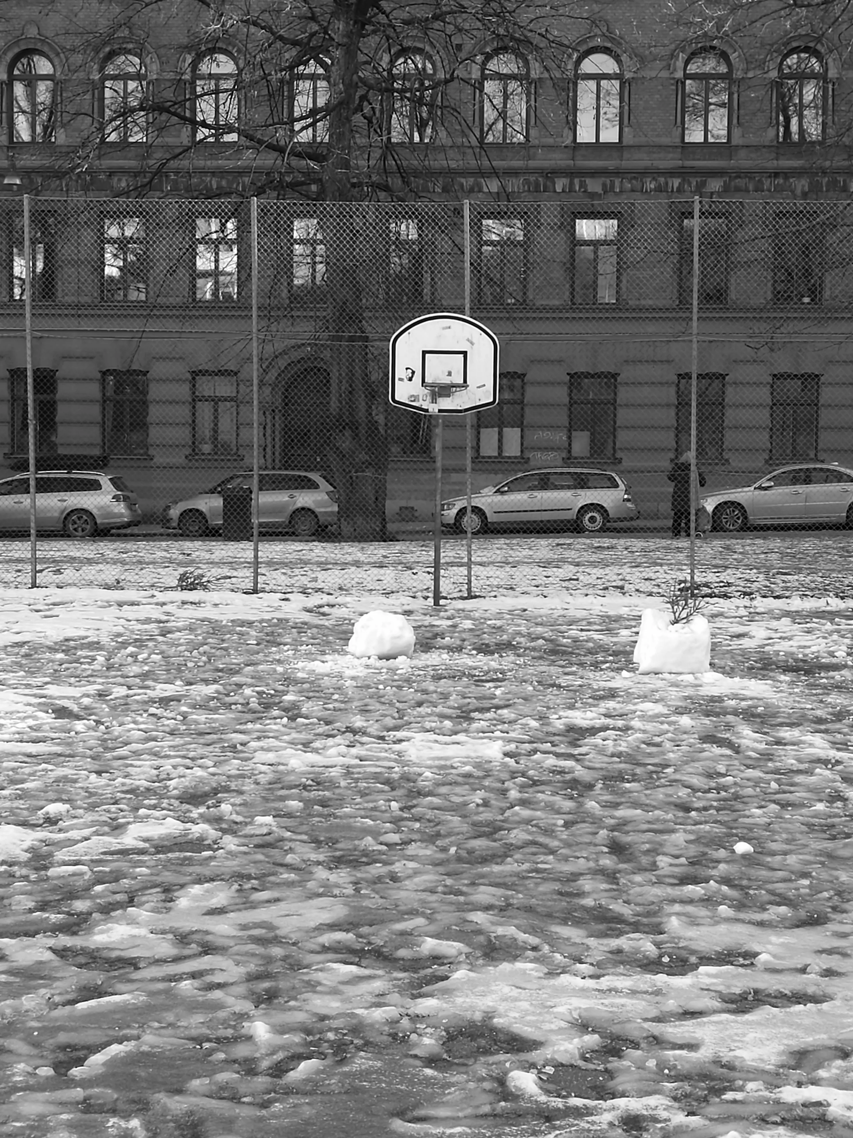 Snow-covered basketball court in front of an apartment building